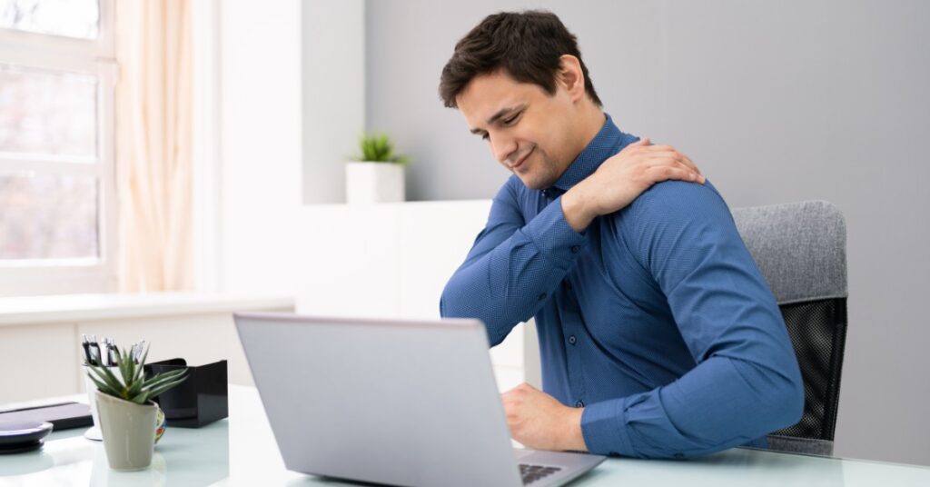 Man at a Desk Looking at a Computer With Shoulder Pain | St. Johns Chiropractic & Performance